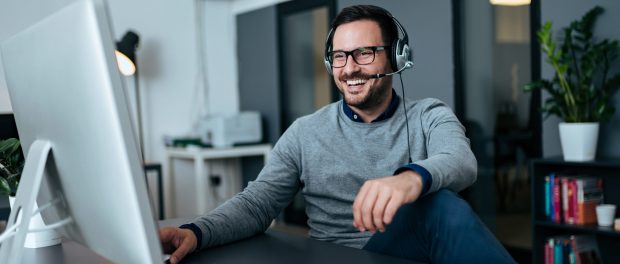 Handsome casual businessman talking online via headset.